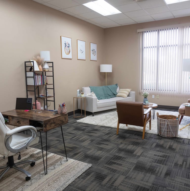 an office room with a couch, chair, and a table