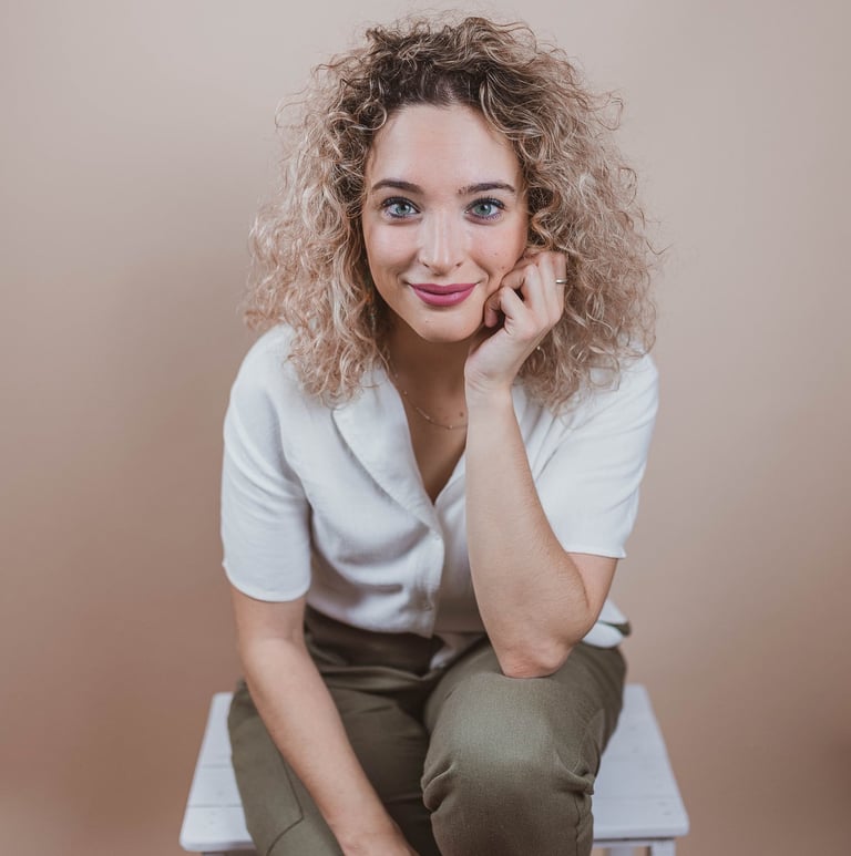 a woman sitting on a chair with her hand on her chin