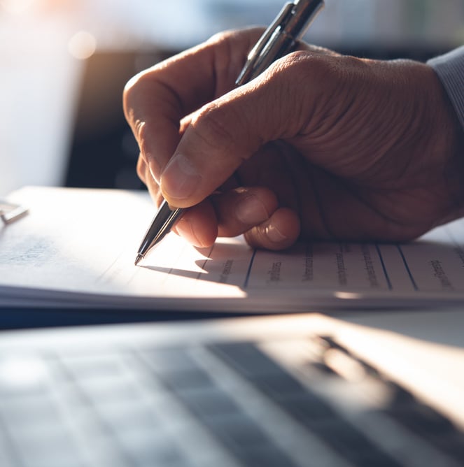 Man signs agreement using a pen on paper