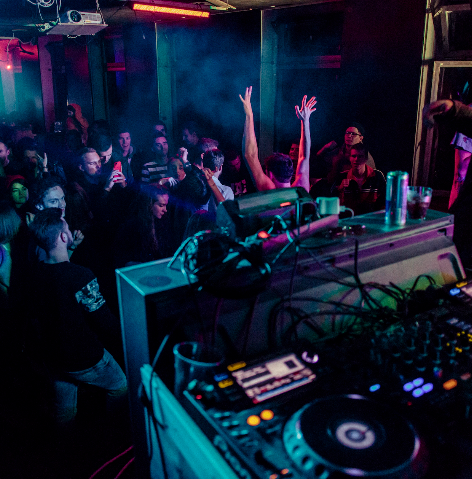a dj spinning tunes in a nightclub on Pioneer CDJ turntables