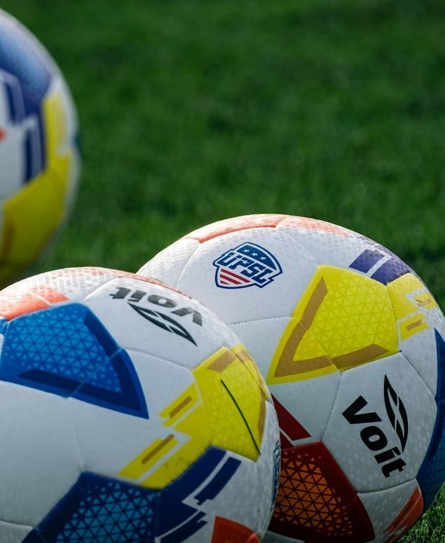three soccer balls on a field with a soccer ball