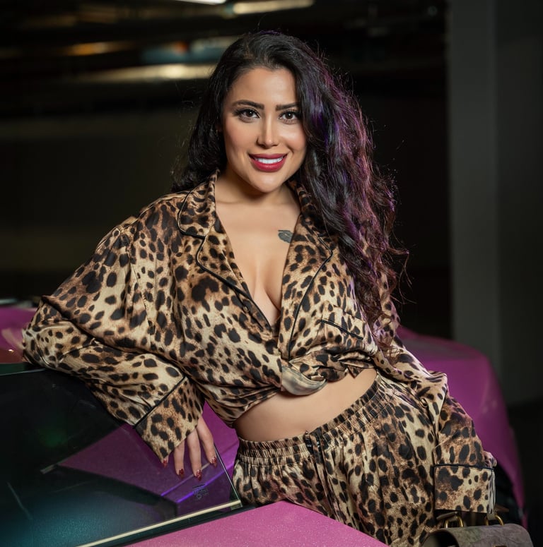 Smiling model in leopard outfit leaning on pink Lamborghini, photographed by Fred Art Studio.