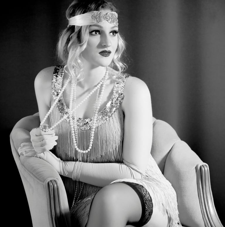 Attractive blonde female wearing classic flapper beaded dress, long strands of pearls and headband