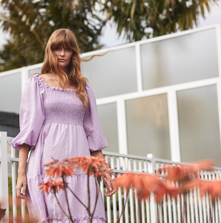 Fashion campaign photography - a woman in a purple dress standing in front of a fence
