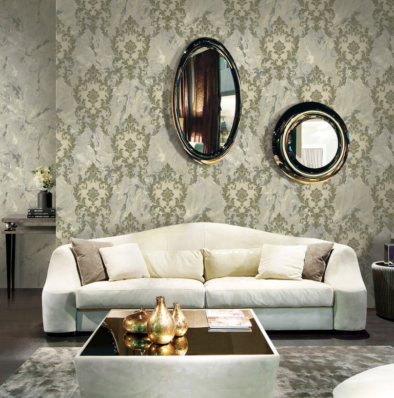 Luxury living room featuring damask wallpaper, a modern white sofa, and decorative oval wall mirrors.