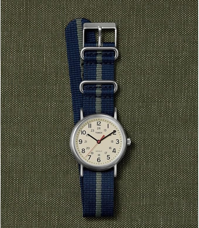 Timex Weekender watch with a blue and grey nylon NATO strap on a green canvas background.