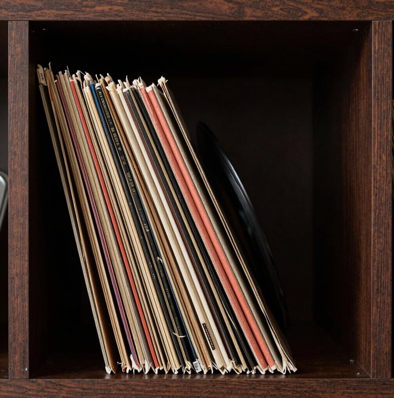 An artistic shot of vintage vinyl records stacked vertically in a dark cocoa brown wooden shelf. The edges of the records catch a muted terracotta light, creating a sophisticated and warm artistic atmosphere.