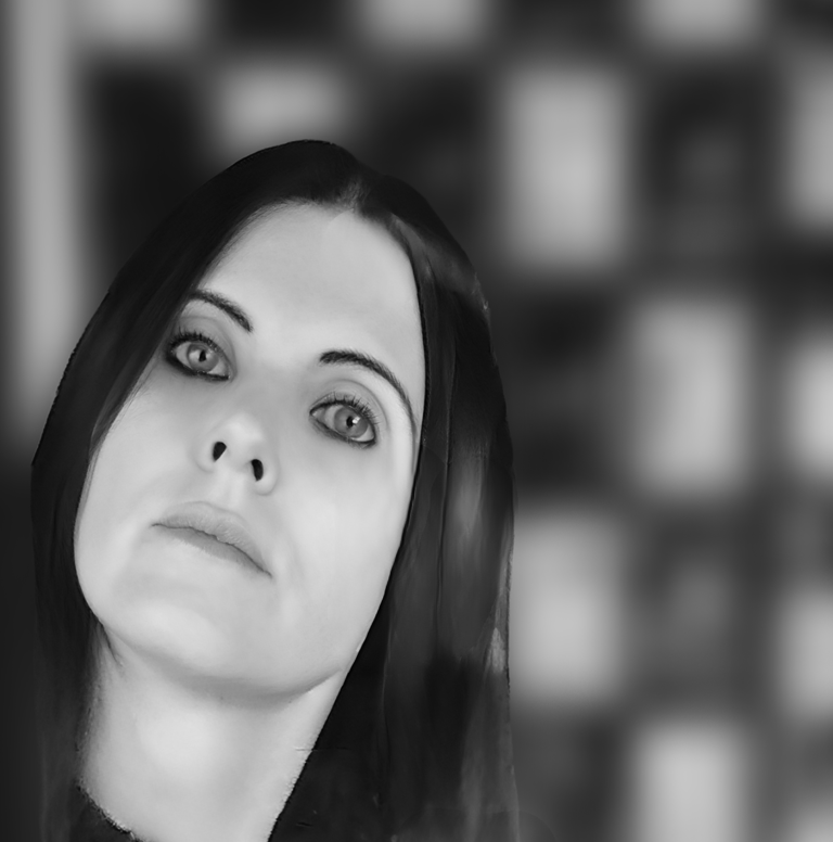 Black and white portrait of a woman with long dark hair and dramatic eye makeup against a blurred background.