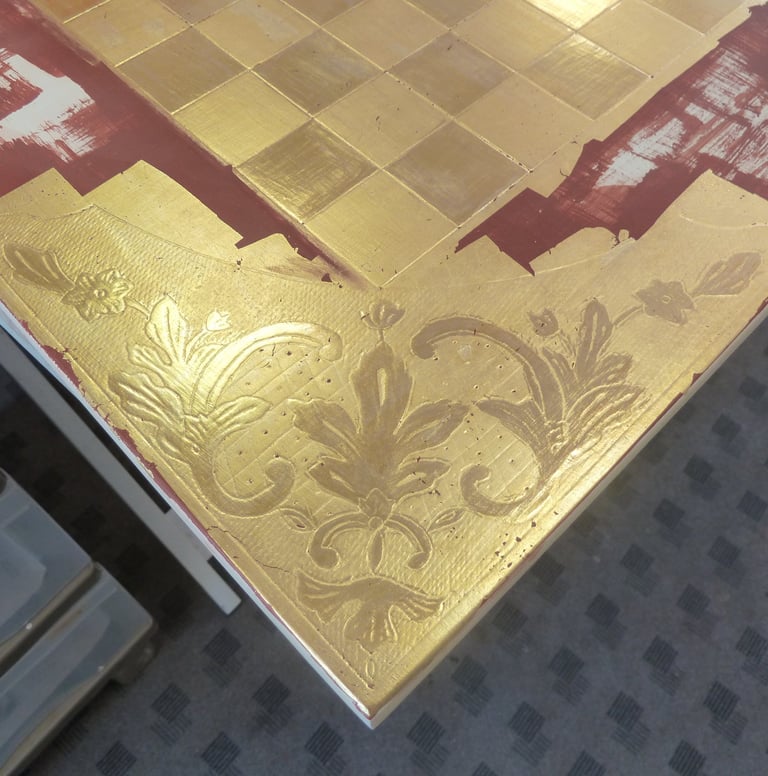 Détail de la pose de dorure à la feuille d'or pour le décor d'un échiquier.
