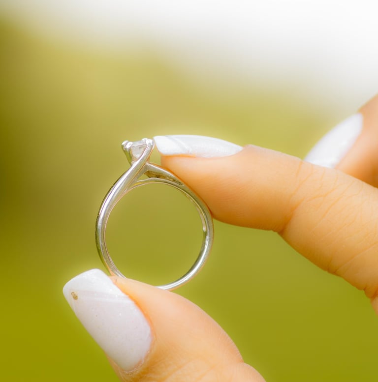 Hermoso anillo de compromiso sostenido por la novia con sus dedos  pulgar e indice. 