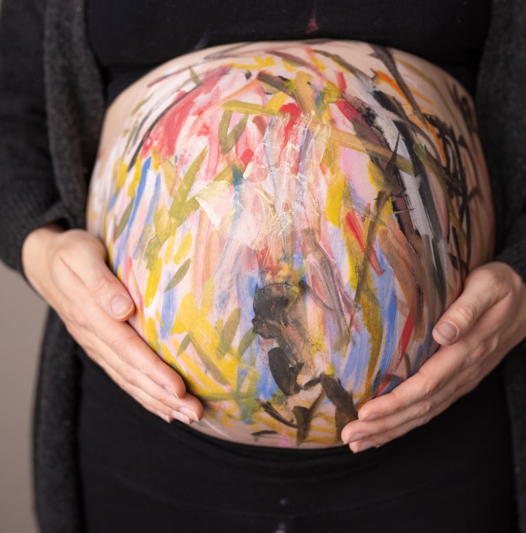 Babybauch mit bunter Farbe angemalt als Bellypainting