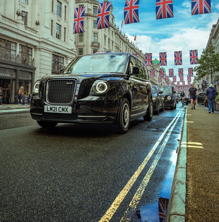 táxi preto tradicional circulando por rua de Londres com bandeiras britânicas