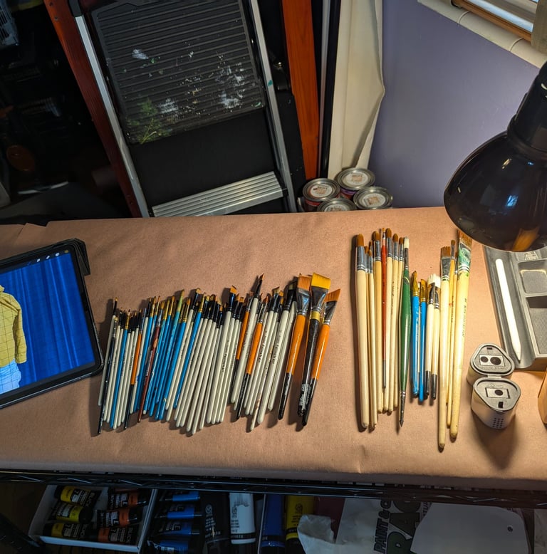 Art studio setup with iPad, brushes of all sizes, sketching pencils, pencile sharpener, paints, and light.