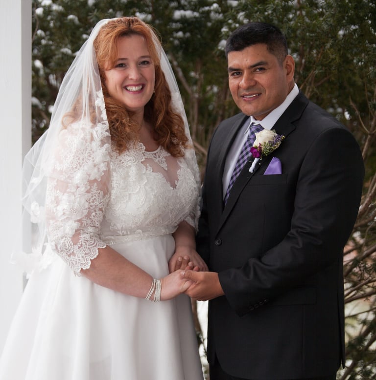 a man and woman in wedding attire standing in front of a white house