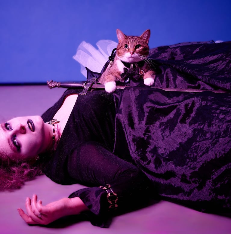 a girl in a black dress dying on the ground with a cat holding a sword on top of her body