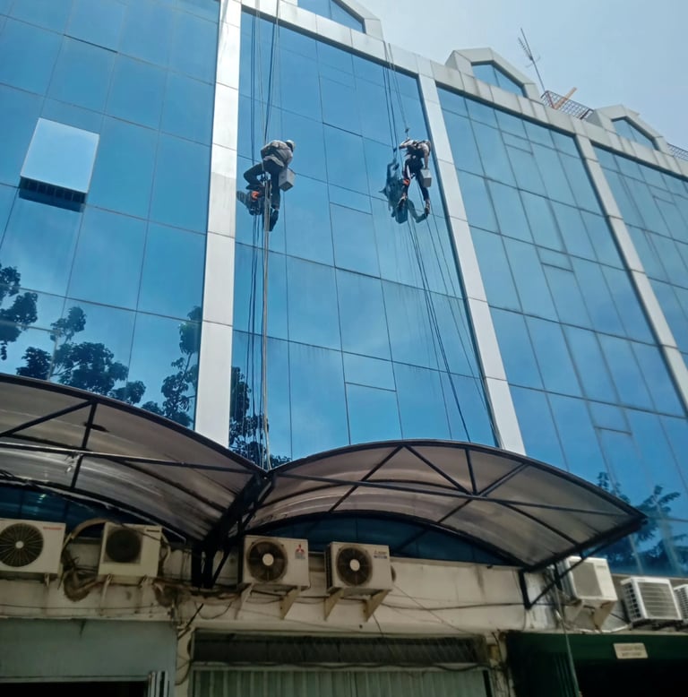a man is cleaning a building with a window cleaner