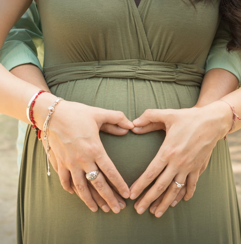 a pregnant woman in a green dress with her hands on her belly