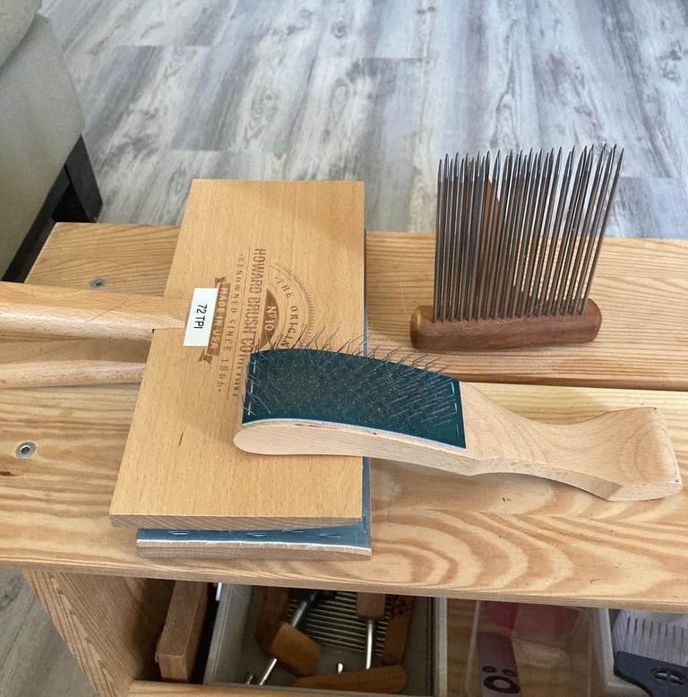 Wool carders and a comb on a wooden bench