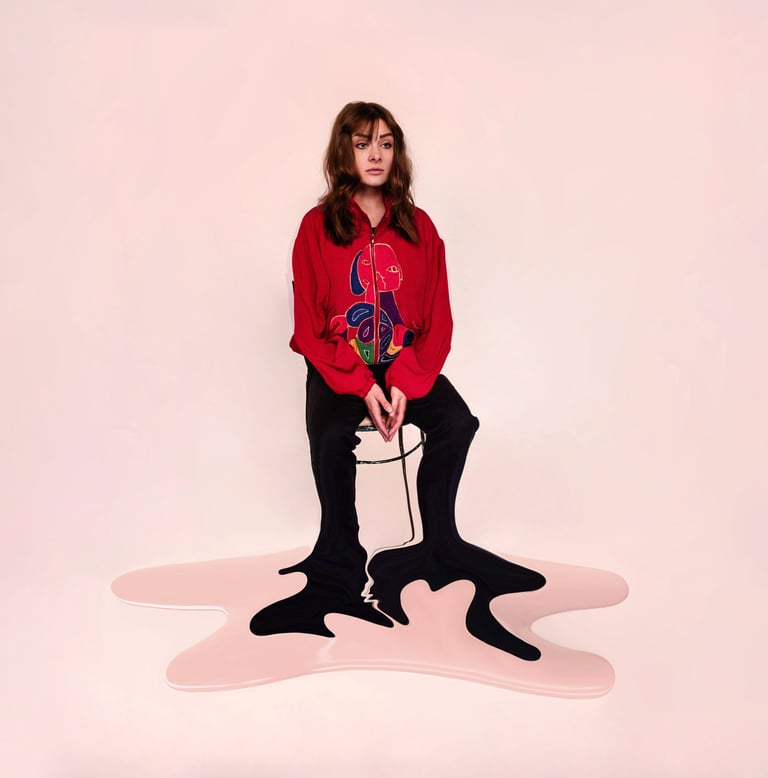 Surreal fashion portrait of a woman in a red jacket with legs melting into a pink floor puddle.