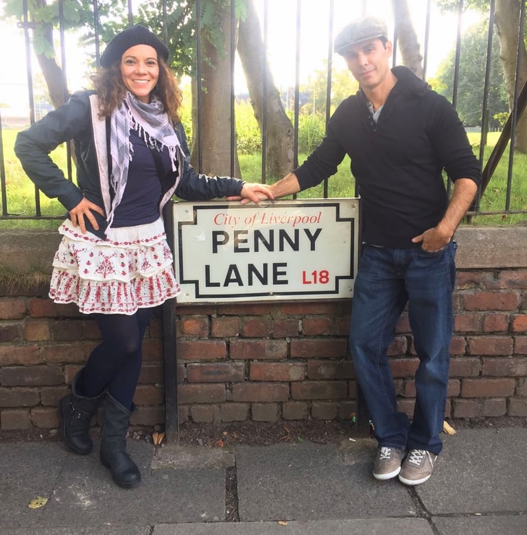 Couple standing in front of Penny Lane street sign in Liverpool England from Beatles song