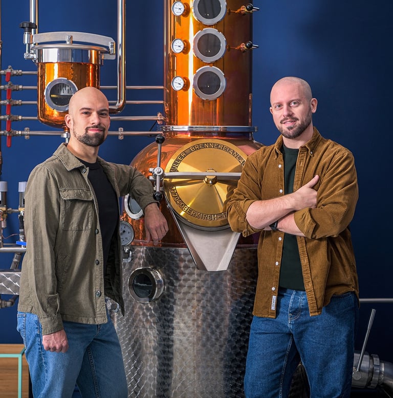 master distiller e designer in posa professionale davanti ad un alambicco di rame e acciaio