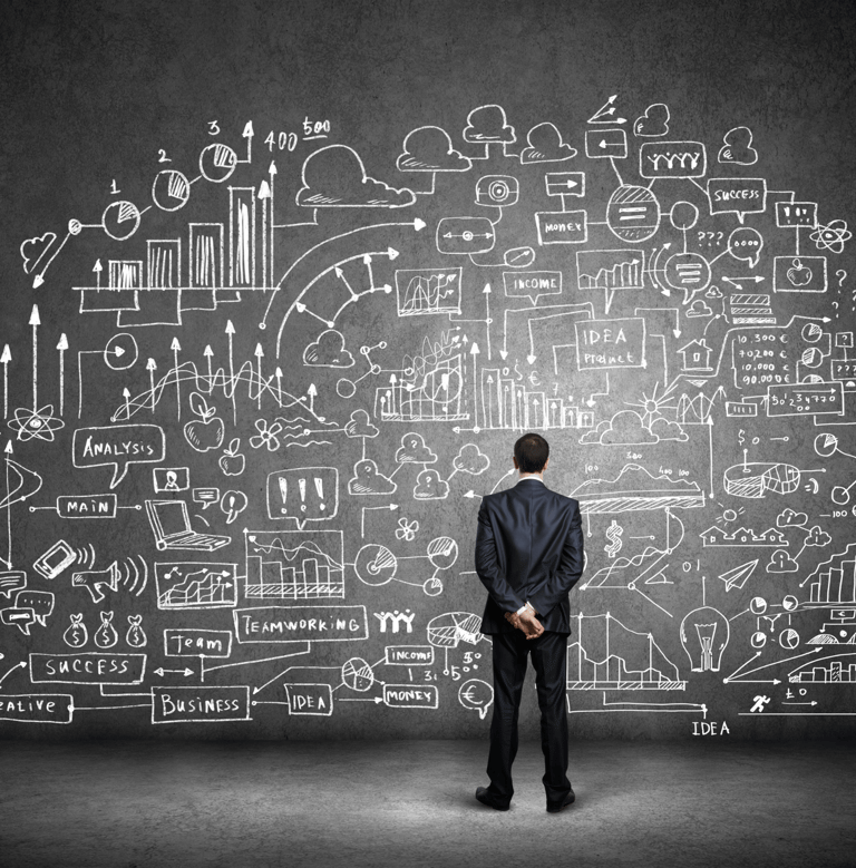 a man in a suit standing in front of a chalkboard with a drawing of
