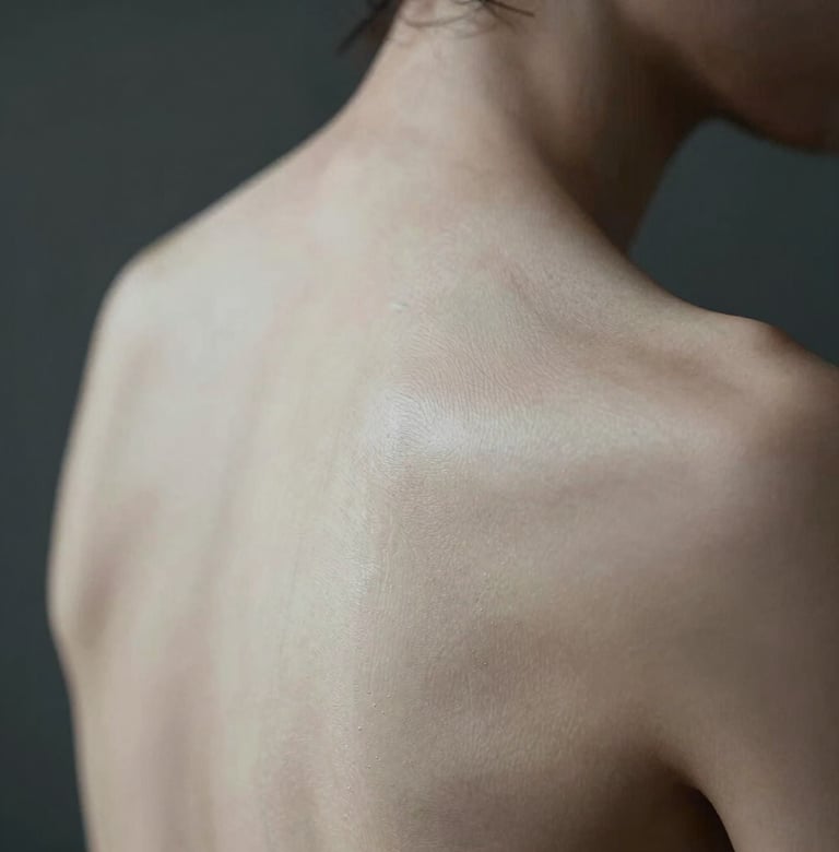 Artistic macro photography of the human form, focusing on the organic textures and lines of the skin. Soft lighting in a dark room, charcoal and off-white tones, North American style.