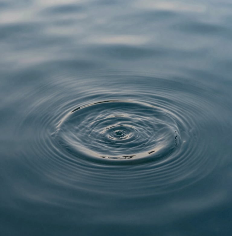 An abstract close-up of water ripples in a slate blue pool, reflecting mist grey light. The composition is clean, calm, and highly professional.