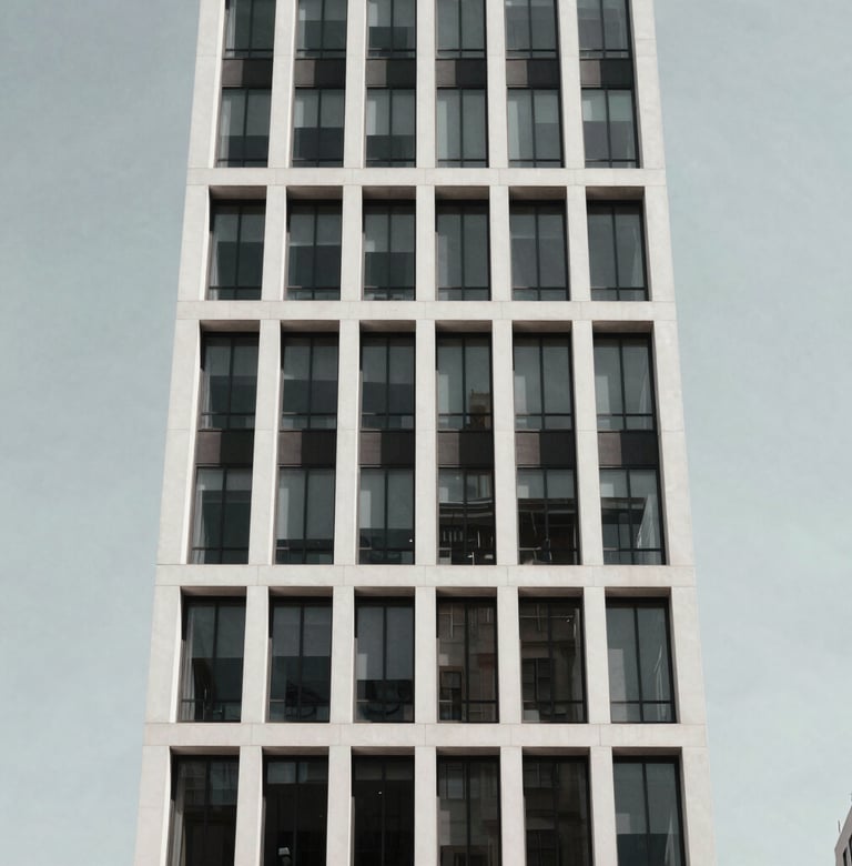 A low-angle shot of a minimalist modern building facade in New York City. The structure features clean white lines and glass against a clear, pale gray sky. The composition is centered and bold, reflecting a sophisticated and aspirational urban vibe.