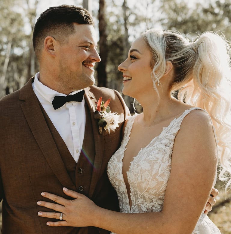 a bride and groom standing in a wooded area