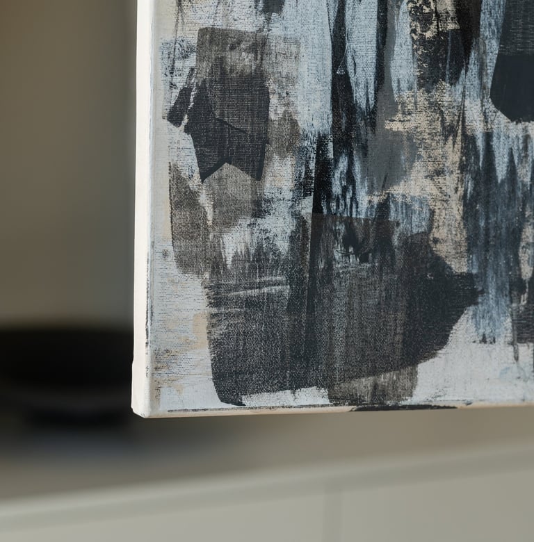 Close-up of a modern abstract canvas painting with black and grey brushstrokes on a textured white background.