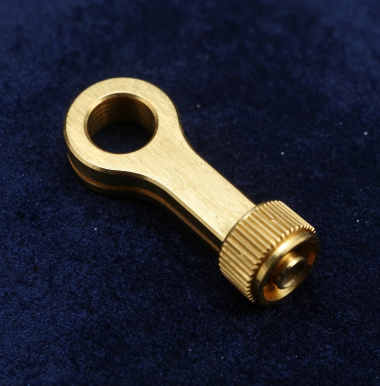 Macro photography of a custom-designed brass prop accessory sitting on a dark midnight blue velvet surface. The lighting is precise, highlighting the metallic sheen and meticulous craftsmanship. Western European luxury editorial style.