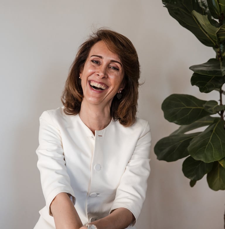 a female life coach in a white suit, smiling