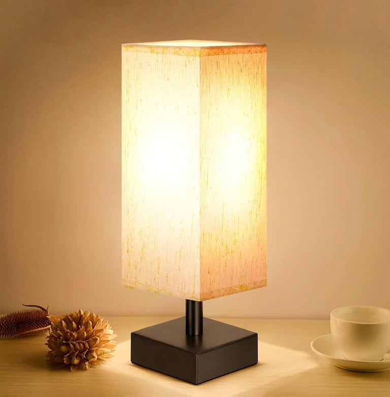 Modern square bedside table lamp with a rectangular beige fabric shade and a black metal base.