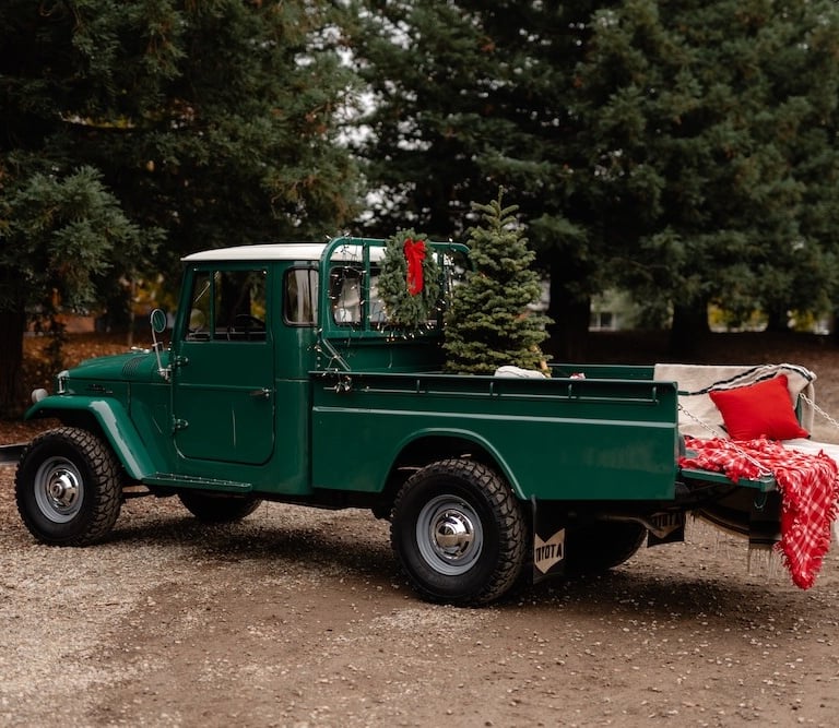 A photo of a green 1967 Toyota Land Cruiser pickup in a wooded setting.