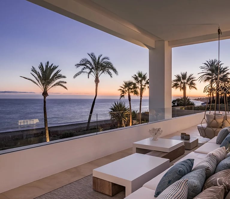Covered terrace seating area at dusk with sea horizon