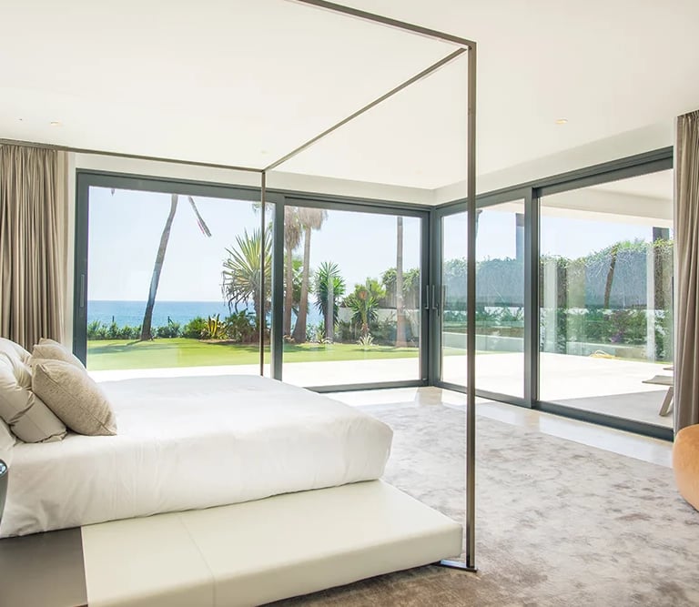 Master bedroom with floor to ceiling glazing and garden views