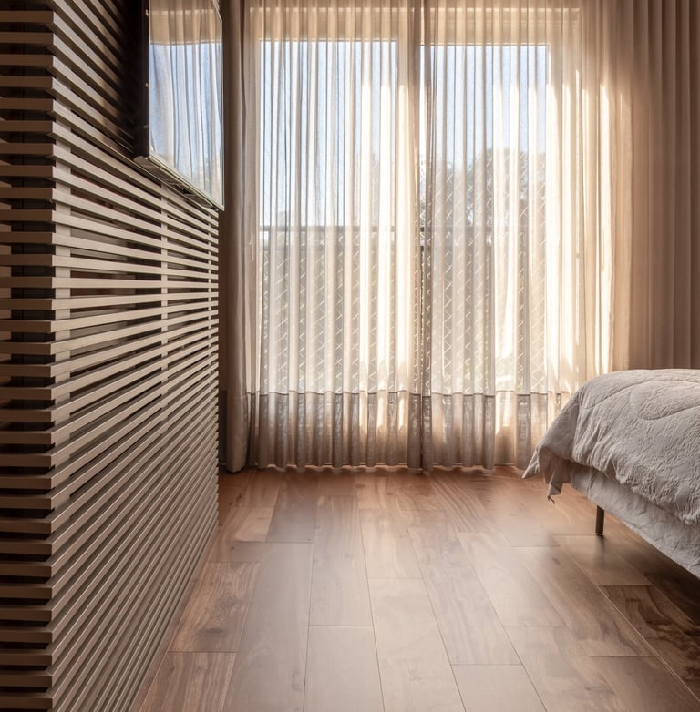 quarto com piso de madeira natural, painel ripado, cama e cortina wave