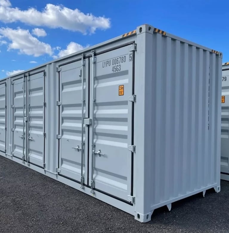 A row of light gray metal shipping containers for secure storage under a clear blue sky.