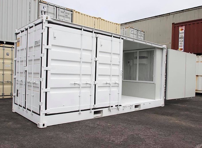 Modified white shipping container with an open side door used for portable storage or mobile office.