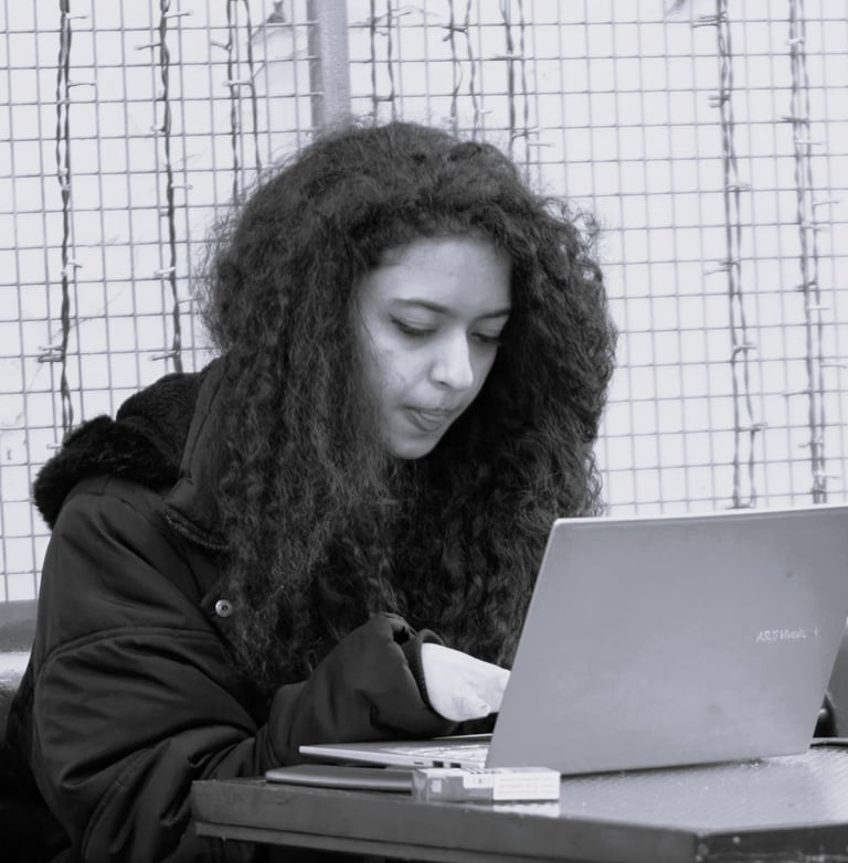 a woman with curly long hair sitting at a table with a laptop