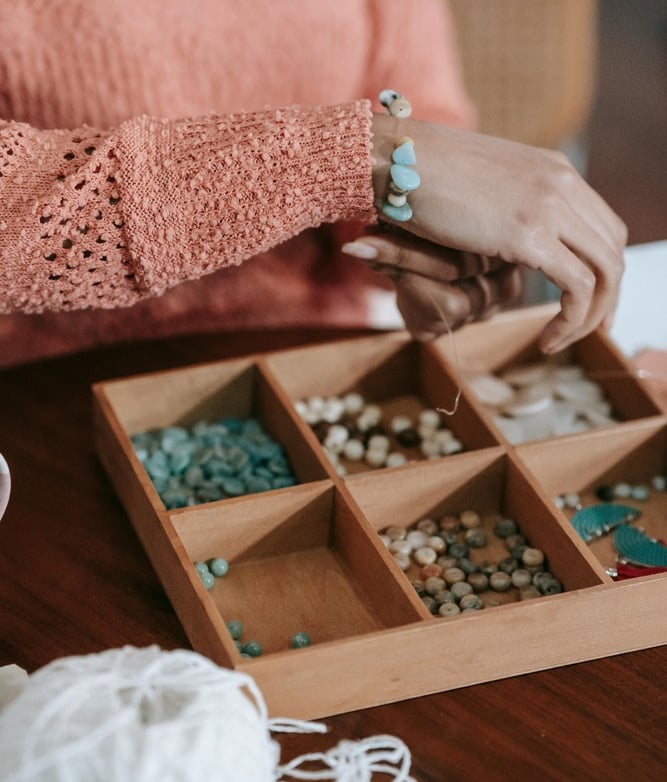 mujer creando una pulsera con piedras naturales 