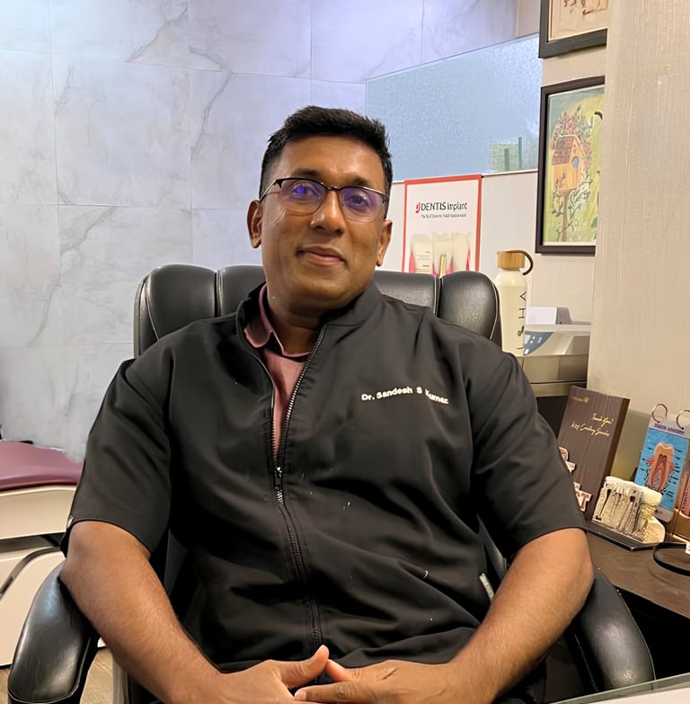 Dr. Sandesh Kumar, an experienced implant dentist, sitting in his dental clinic office.