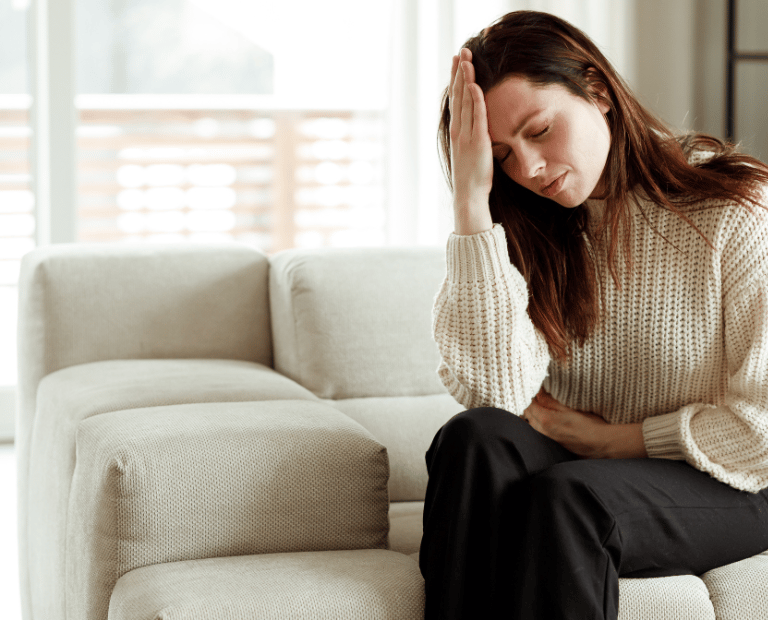 woman with hand on forehand experiencing migraine or pain