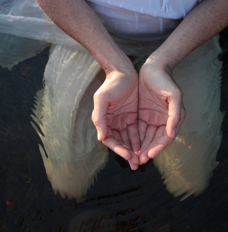 Deux mains sont jointes en coupe dans l'eau.