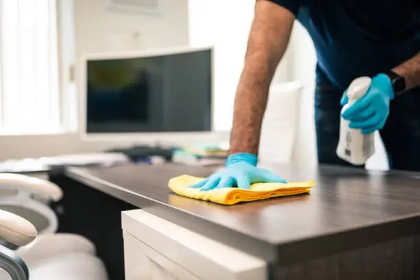 a man cleaning a desk with a sponge pad