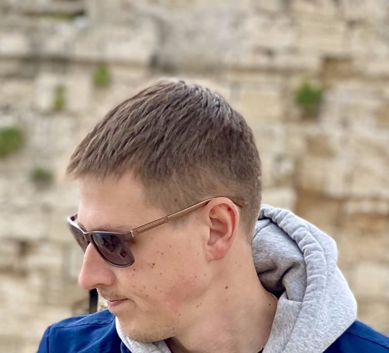 a man in a blue jacket and sunglasses posing in Medieval town in Rhodes Greece