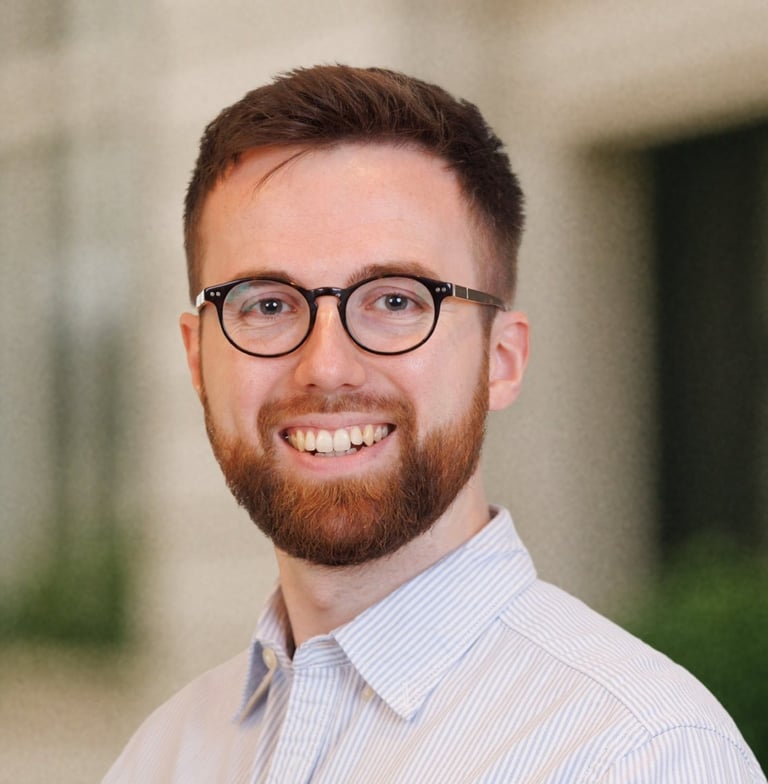 a man with a beard and glasses on a city street
