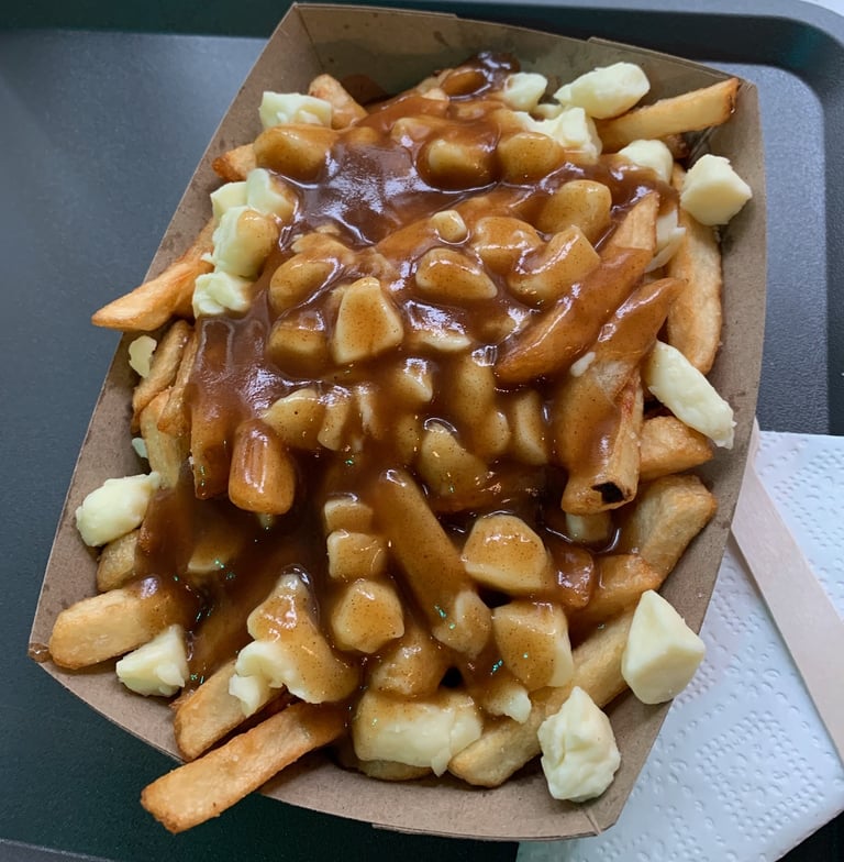 A large boat of Poutine: French fries covered in white cheese curds and brown gravy