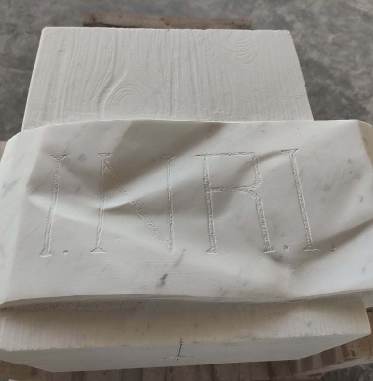 Hand-carved white marble sculpture featuring the INRI inscription with realistic fabric folds.